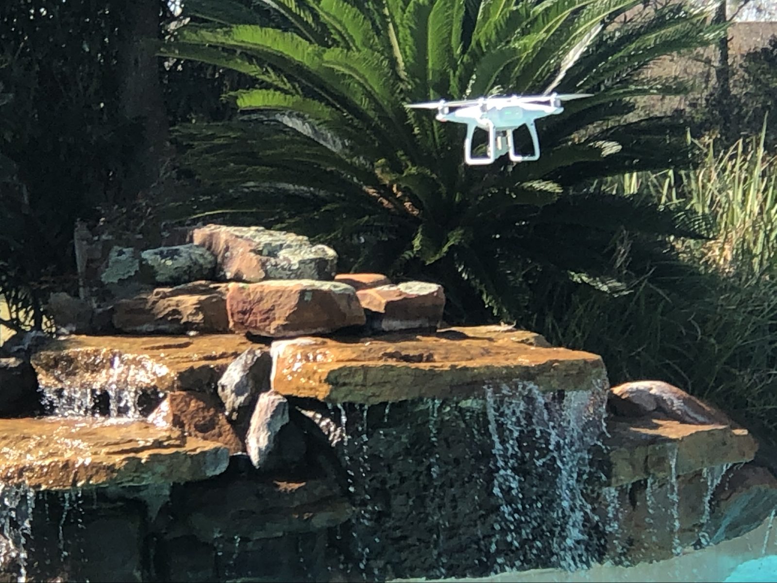 Multi-tier natural flagstone rock waterfall cascading into a Houston-area custom pool by Creative Lifestyle Pools
